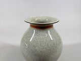 un vase gris bordé de brun, posé sur une table