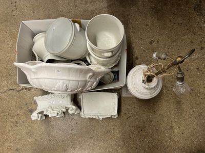 beaucoup d'assiettes et de tasses blanches dans une boîte posée par terre