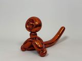 a shiny orange cat statue sitting on a white surface
