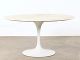 une table ronde avec un piètement blanc et un plateau en bois
