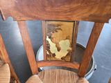a wooden chair with a painting on the back of it