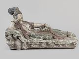 l'image d'une statue de femme assise au sommet d'un rocher