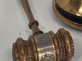 a wooden gaven and a brass bell on a white table