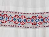 a close up of a white dress with a red and blue pattern on it