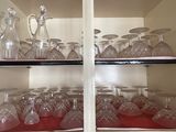 bottles and glasses on a shelf in a cabinet with a red cloth