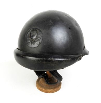 un vieux casque noir avec une base en bois sur fond blanc