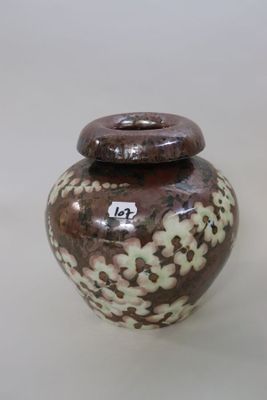 a brown and white vase sitting on a white surface