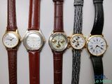 four different types of watches are lined up on a white surface