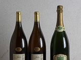 three bottles of wine are lined up on a wooden table