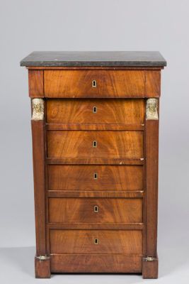 a walnut chest of drawers with black marble top