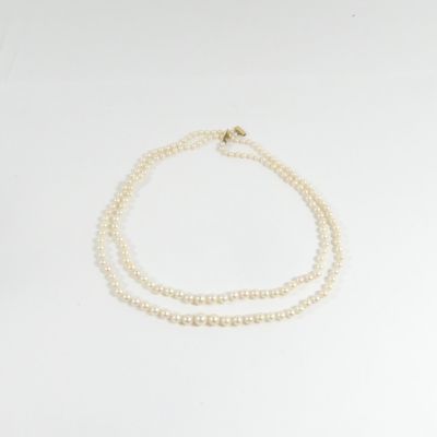 un collier de perles blanches avec un fermoir en or sur fond blanc