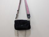 pink and black purse with chain strap hanging on a wall