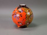 an orange vase with a design on it on a gray surface