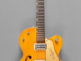 une vieille guitare électrique jaune posée sur une surface grise