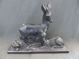 statue représentant un cerf et un chien posés sur un socle, sur fond gris