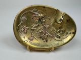 an image of a gold plate with a bird and flowers on it