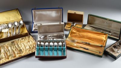 de nombreux articles d'argenterie rangés dans un coffret posé sur une table