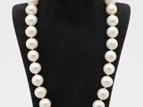 a white pearl necklace on a black mannequin