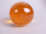 an orange glass ball sitting on a white surface