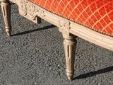 an orange upholstered bench sitting in the middle of a parking lot