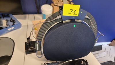 un haut-parleur bleu et noir posé sur un bureau, sur lequel est collé un autocollant jaune