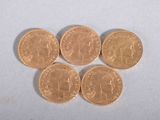 four gold coins sitting on top of each other on a white surface