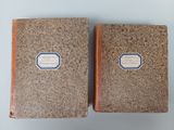two brown books sitting on top of a table next to each other