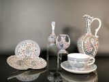 une table en verre sur laquelle se trouvent un vase, une assiette et des tasses