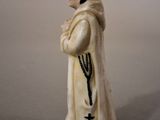 figurine of a man in a white robe with a cross on his chest