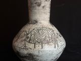 un vase blanc orné d'un motif sur un fond noir