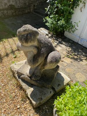 une statue représentant un ours assis sur un bloc de pierre