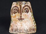 un gros plan d'une sculpture en céramique représentant un visage sur fond noir