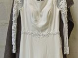 a white dress hanging on a hanger in front of a brick wall