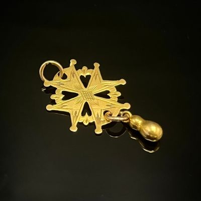 une image représentant un pendentif en forme de flocon de neige doré posé sur une surface noire
