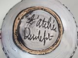 a hand holding a white bowl with writing on it
