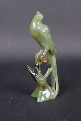 a green bird sitting on a branch of a tree