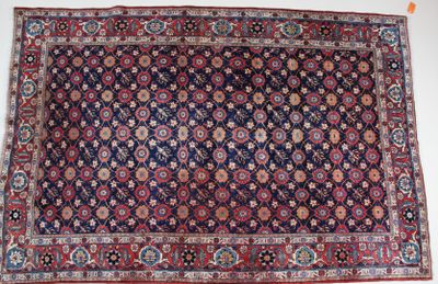 Un tapis persan ancien est posé sur une surface blanche