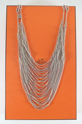 a close up of a silver chain necklace on an orange background