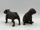 pair of bronze figurines of two dogs on a white surface