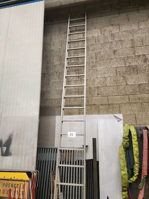 une échelle appuyée contre un mur, à côté d'une pile de bagages