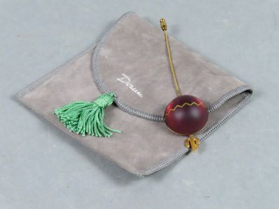 a red apple with a tassel on a gray bag