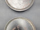 two metal pans sitting on top of a table covered in dirt