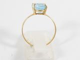 a close up of a gold ring with a blue topaz stone