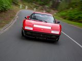 a red sports car driving down the road on the side of the road