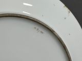 a white plate with a gold rim on a black table