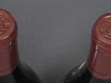 two bottles of red wine sitting next to each other on top of a table