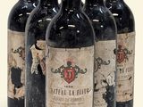 quatre bouteilles de vin sont alignées sur une surface blanche