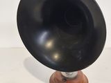 a black speaker on a wooden stand with a cord around it