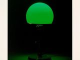 a green lamp sitting on top of a table next to a black wall