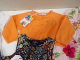 a baby girl ' s dress and cardigan on a bed